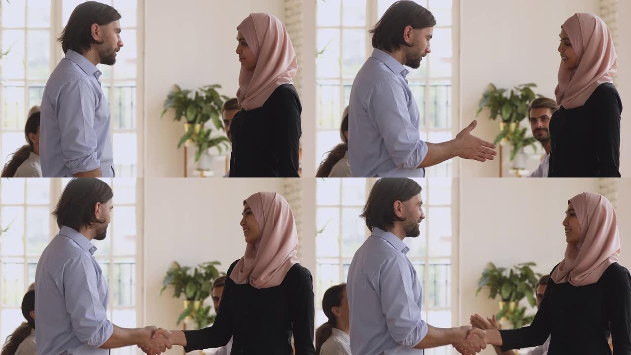 自信的男组长握手赞扬阿拉伯女同事。