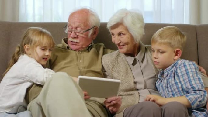 祖父母与孙子孙女在平板电脑上玩游戏