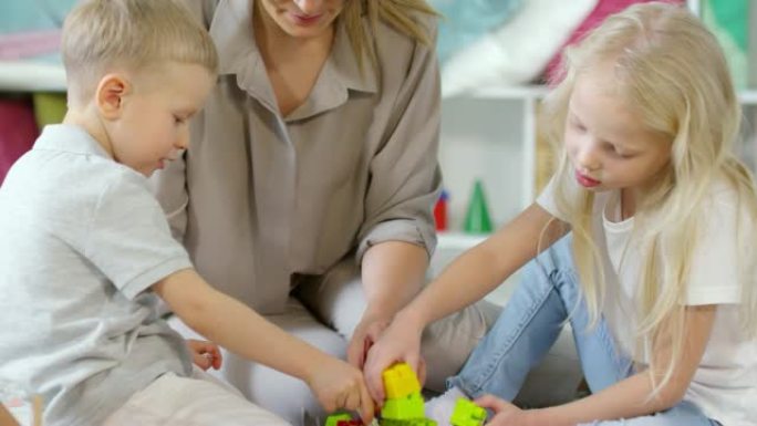 小孩子和女教师玩建筑玩具