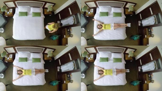 自上而下: 放松假期的年轻女子跳到酒店房间的床上。