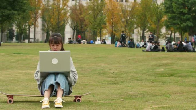 亚洲女大学生在校园草坪上使用笔记本电脑