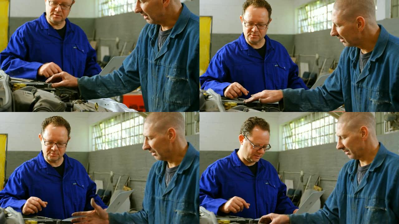 机械师在他的同事使用笔记本电脑4k时检查汽车