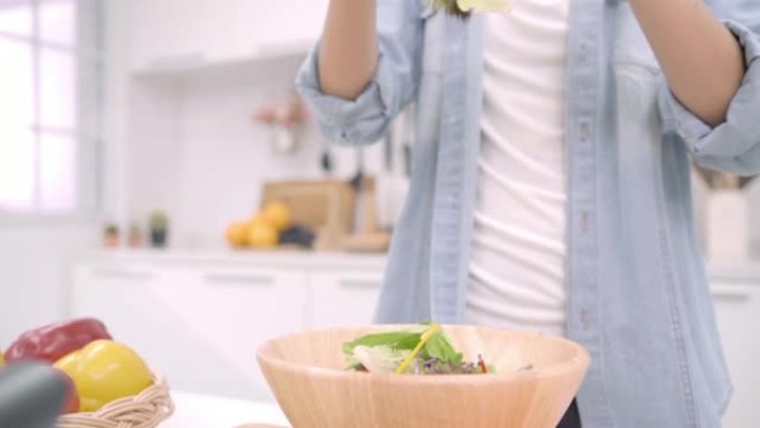 慢动作-年轻的亚洲女性在厨房里做沙拉健康的食物，美丽的女性在休闲中使用有机蔬菜大量的营养准备沙拉，以