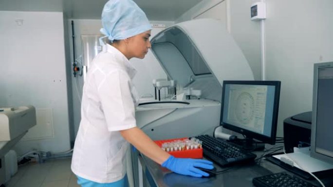 一个女人把血样放在架子上。护士处理血液样本，在计算机中检查信息。