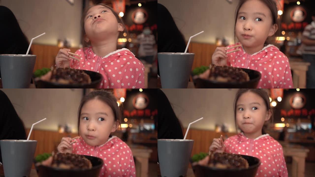 漂亮的小女孩在日本餐厅吃炸猪饭