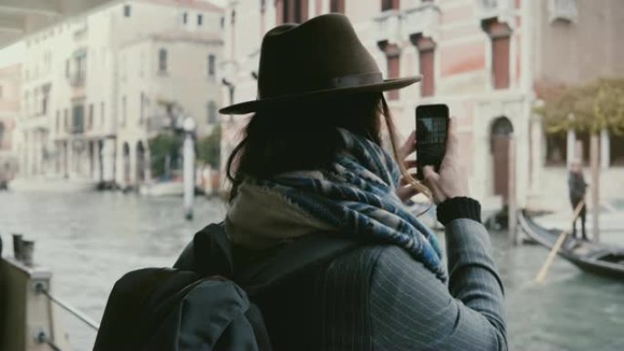 在威尼斯度假期间，快乐迷人的高加索女商人在贡多拉游览中拍摄智能手机照片。