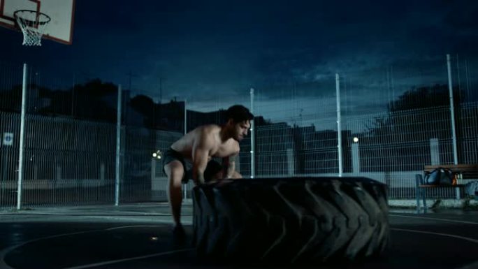 强壮的肌肉健康的年轻光着膀子的男人正在一个有围栏的室外篮球场里做运动。在一个居民区下雨后的一个下午，