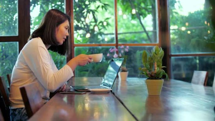 女人用笔记本电脑工作，在咖啡馆喝咖啡