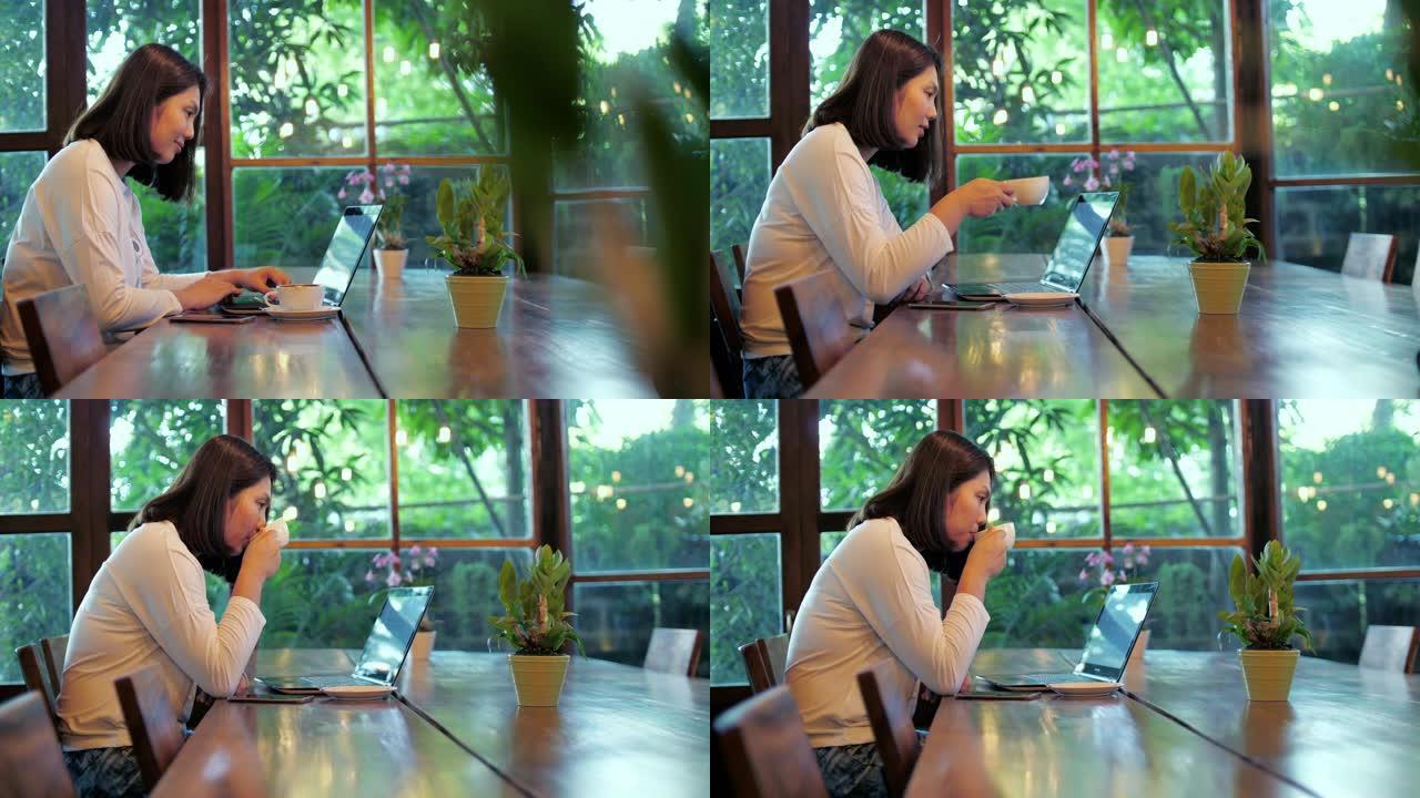 女人用笔记本电脑工作，在咖啡馆喝咖啡