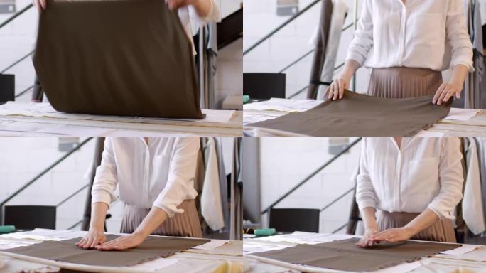 女裁缝师在缝纫工作室的桌子上摆放布料