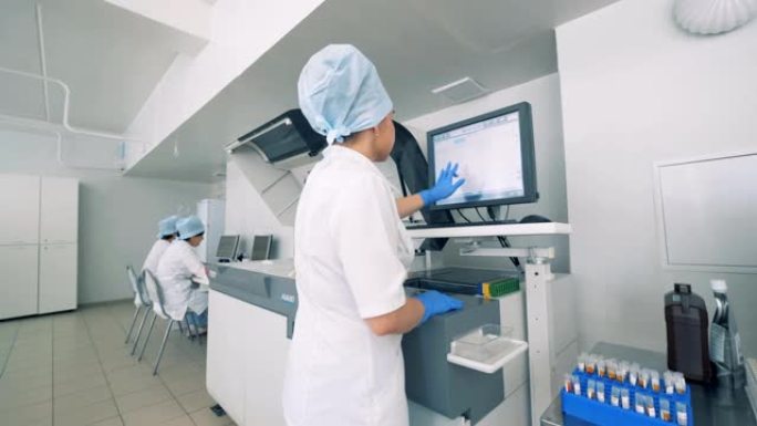实验室设施与女性实验室专家与触摸屏上的自动制药设备。