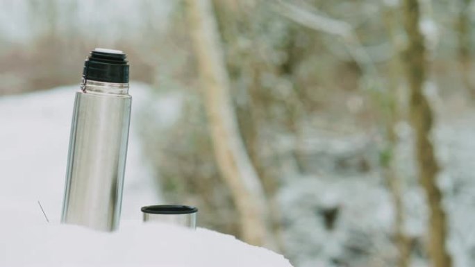 在穿越森林的白雪皑皑的徒步旅行中喝咖啡休息