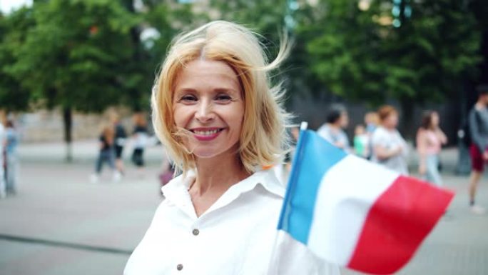 在户外举着法国国旗的漂亮法国女士的慢动作肖像