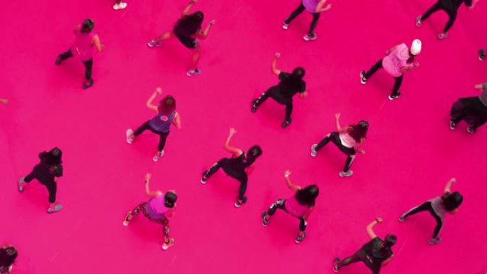 在粉红色地板上的运动课上跳舞的俯视图人群