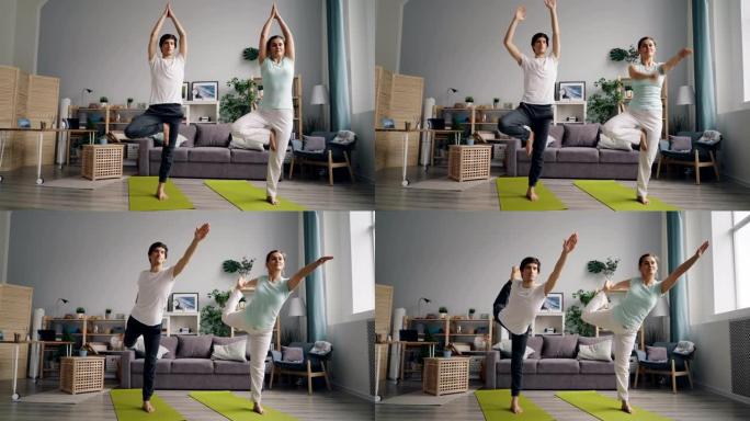 运动情侣在家做瑜伽练习，单腿站在垫子上平衡