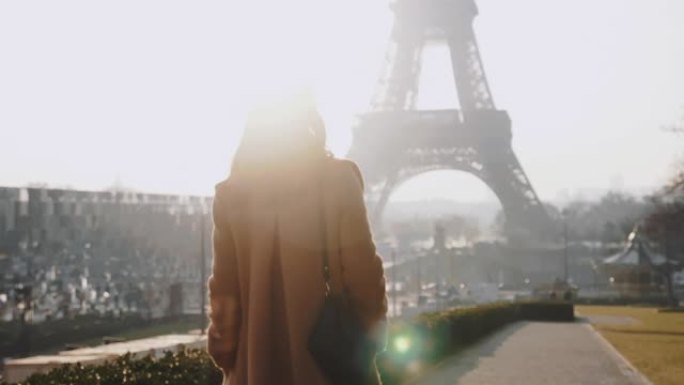 相机跟随快乐优雅美丽的女人沿着史诗般的阳光明媚的巴黎埃菲尔铁塔在Trocadero慢动作附近行走