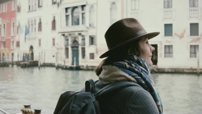 美丽轻松的欧洲旅游女孩看着相机，微笑着在秋季威尼斯神奇的贡多拉游览之旅。