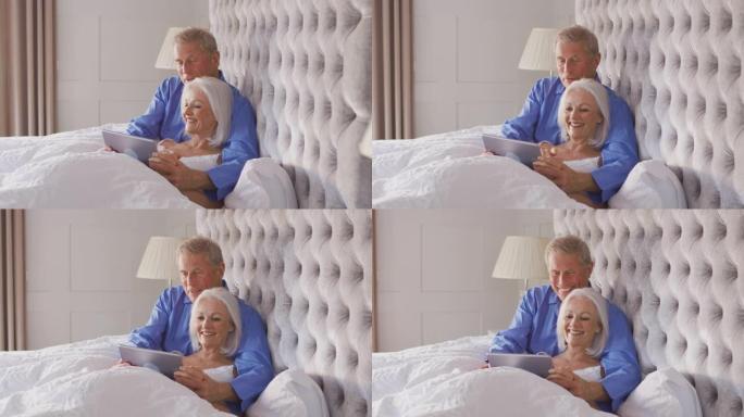 在Covid 19锁定期间，在家中的高级夫妇在床上使用数字平板电脑进行自我隔离
