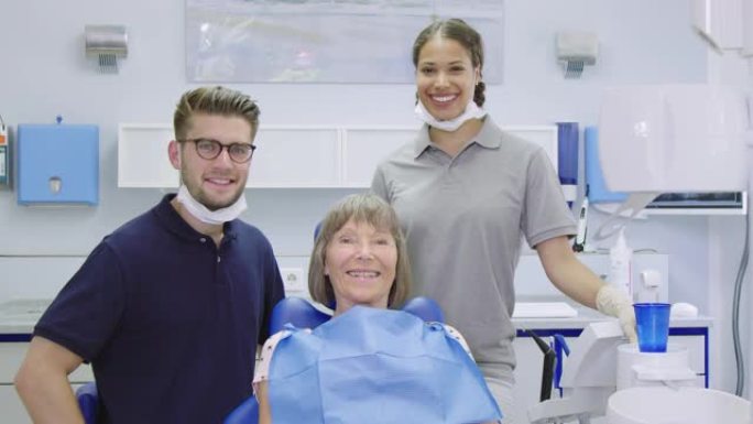 微笑的女人与牙医和护士在诊所
