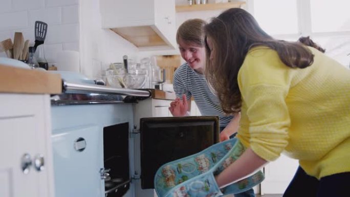 年轻的唐斯综合症夫妇将自制的纸杯蛋糕放入家中厨房的烤箱中