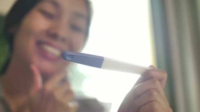 快乐的亚洲女人在检查妊娠试验后感到快乐，结果为阳性