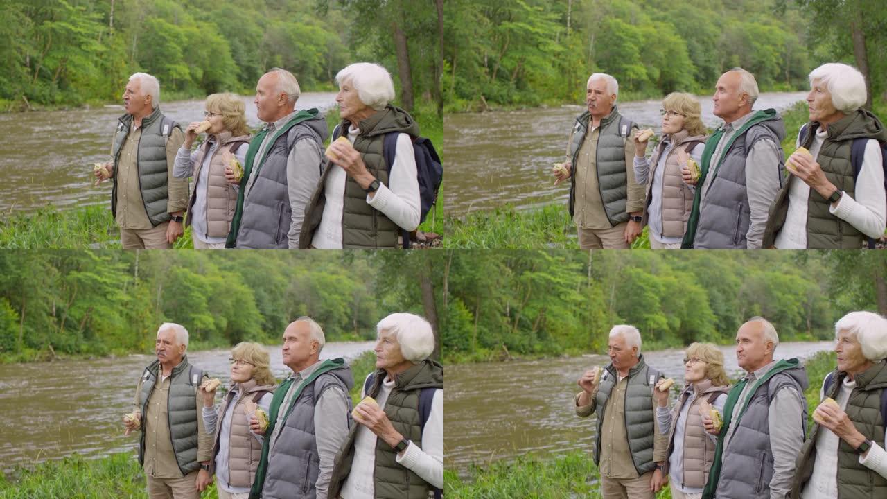 老年游客在河岸上吃三明治