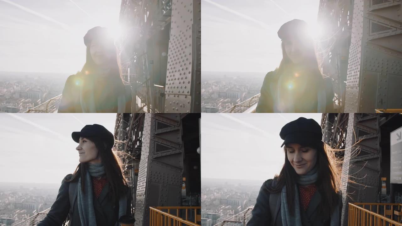 令人惊叹的镜头耀斑拍摄，年轻的旅游女子沿着埃菲尔铁塔的顶部微笑着走向相机。