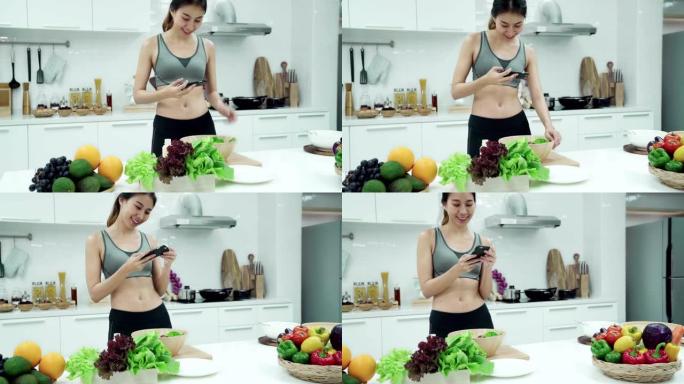 穿着运动服的亚洲女性在周末早上在厨房之家用智能手机拍照并分享照片。健康饮食和健康生活方式理念。