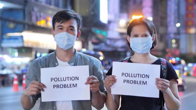 戴着防护面具并拿着纸卡写有 “污染问题” 字样的人。护脸以防止呼吸有毒空气。环境污染，生态灾难，人，