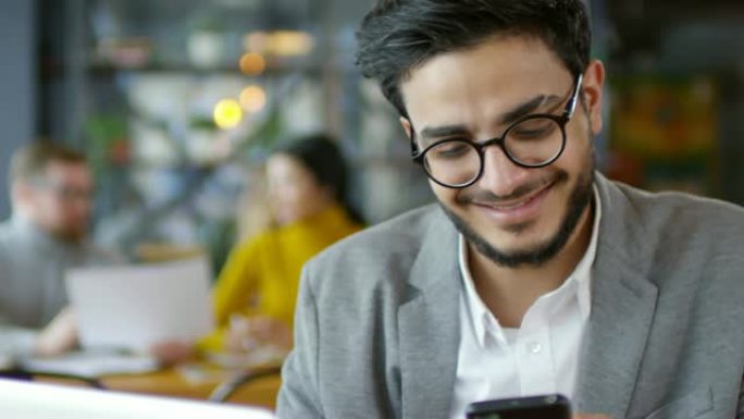 快乐的中东商人在咖啡馆的智能手机上传递消息