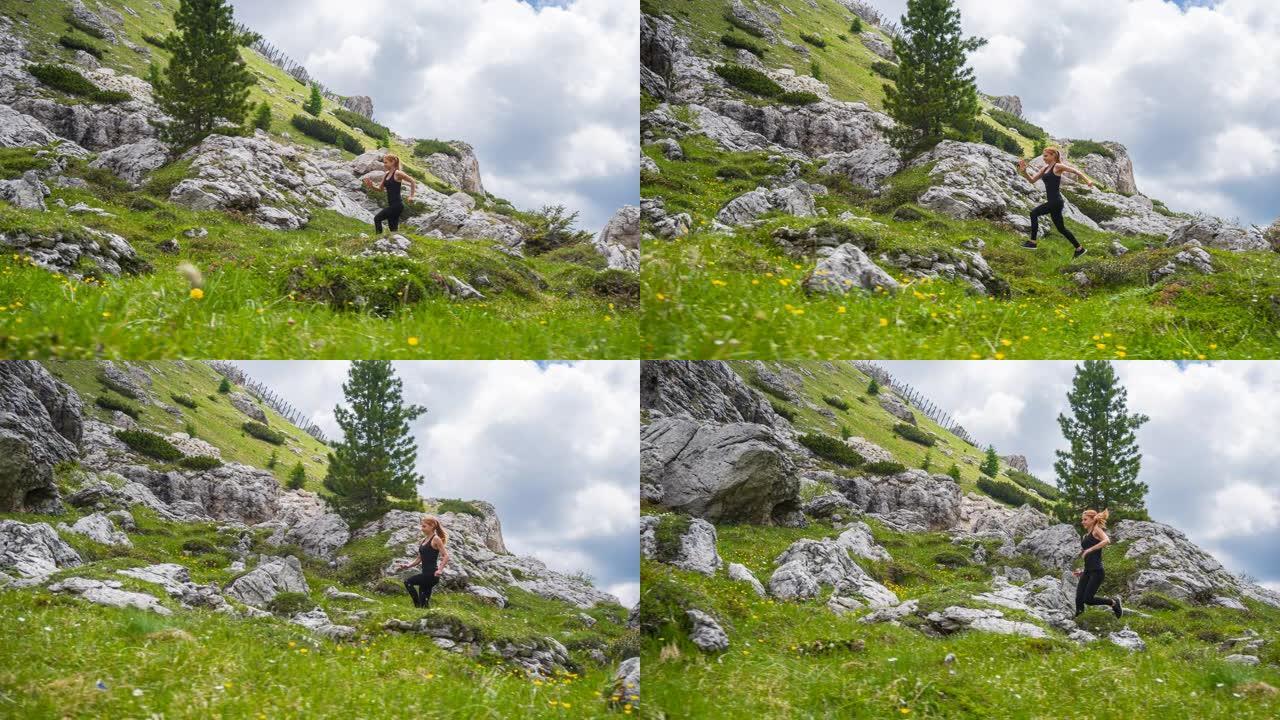 专注的女运动员在山区的岩石小径和草坡上奔跑
