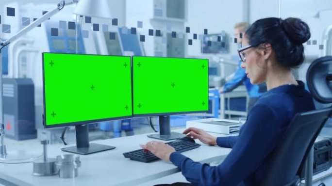 在个人计算机上工作的工业女工程师，两个监视器屏幕是模型屏幕，绿色屏幕，色键显示。拥有高科技机械的现代