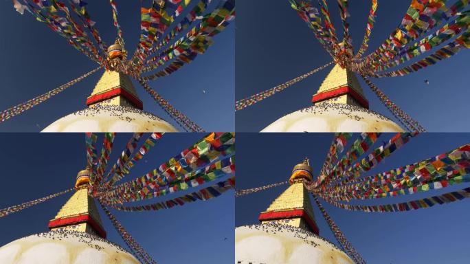 尼泊尔加德满都Boudhanath佛塔周围的彩旗。许多鸟坐在底部。蓝天白月亮。UHD