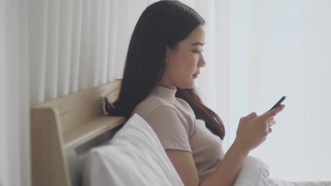 亚洲女性在卧室里使用电话