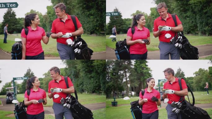 成熟的夫妇打高尔夫球，背着高尔夫球袋，看着记分卡