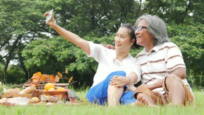 高级夫妇，丈夫和妻子在公园一起使用智能手机自拍。有生活方式、退休年龄和爱情的人。