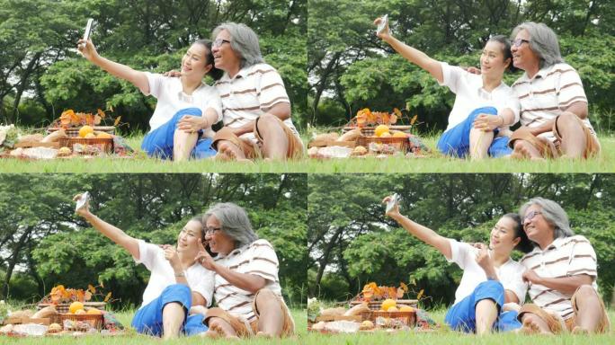高级夫妇，丈夫和妻子在公园一起使用智能手机自拍。有生活方式、退休年龄和爱情的人。