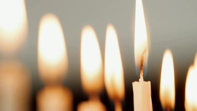 详细拍摄了一组白色蜡烛上的火焰，为犹太节日光明节燃烧，这些蜡烛被吹灭，选择性聚焦