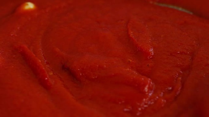 专业厨房的厨师，将红番茄的酱汁与木勺混合。