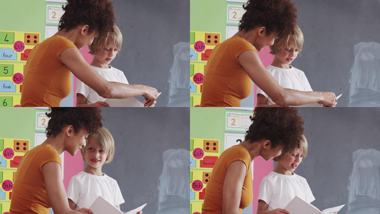 女小学教师在课堂上与男学生一起读书，一对一支持