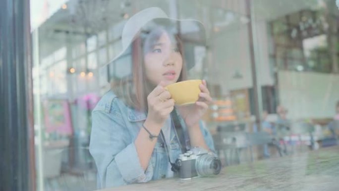 商业自由亚洲女性坐在咖啡馆的桌子上喝一杯温暖的绿茶或咖啡。生活方式聪明美丽的女性在咖啡店概念中放松。