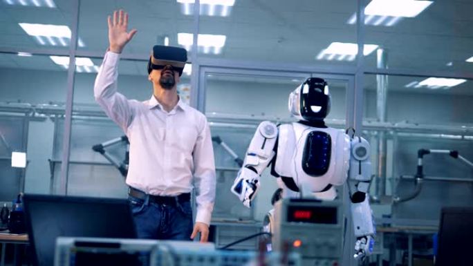 男工人和机器人用手臂做动作。虚拟现实游戏。