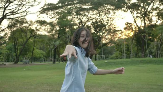 日落时在夏季公园跑步的年轻迷人亚洲女子的慢动作镜头。美丽的女孩在户外享受大自然。