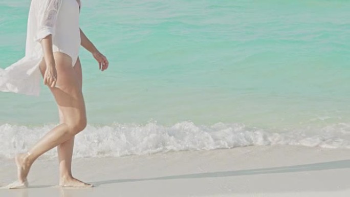 女士女士在马尔代夫白色沙滩上阳光明媚的蓝色海洋冲浪中涉水