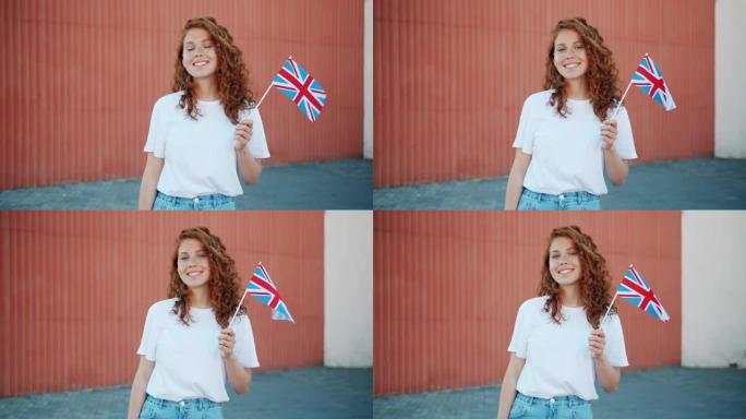 漂亮的红发女孩举着英国国旗在户外微笑着看着相机