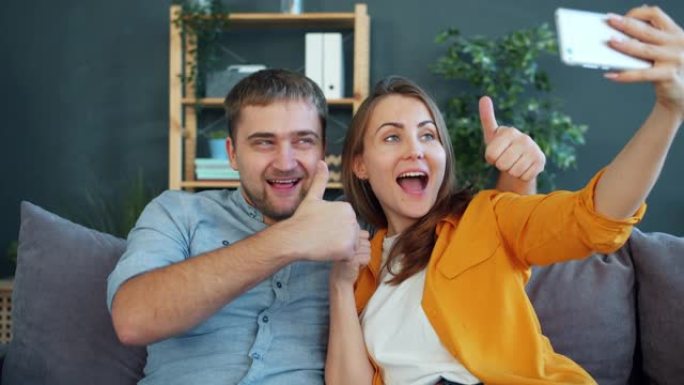 幸福的年轻夫妇在家中用智能手机自拍，摆姿势