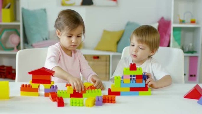 小男孩和女孩在餐桌上玩建筑玩具
