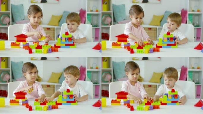 小男孩和女孩在餐桌上玩建筑玩具