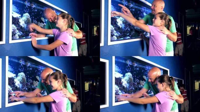 女孩和父亲在水族馆看盐水鱼缸