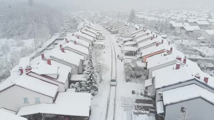 空中: 汽车在雪谷郊区行驶，邻居清理汽车上的积雪